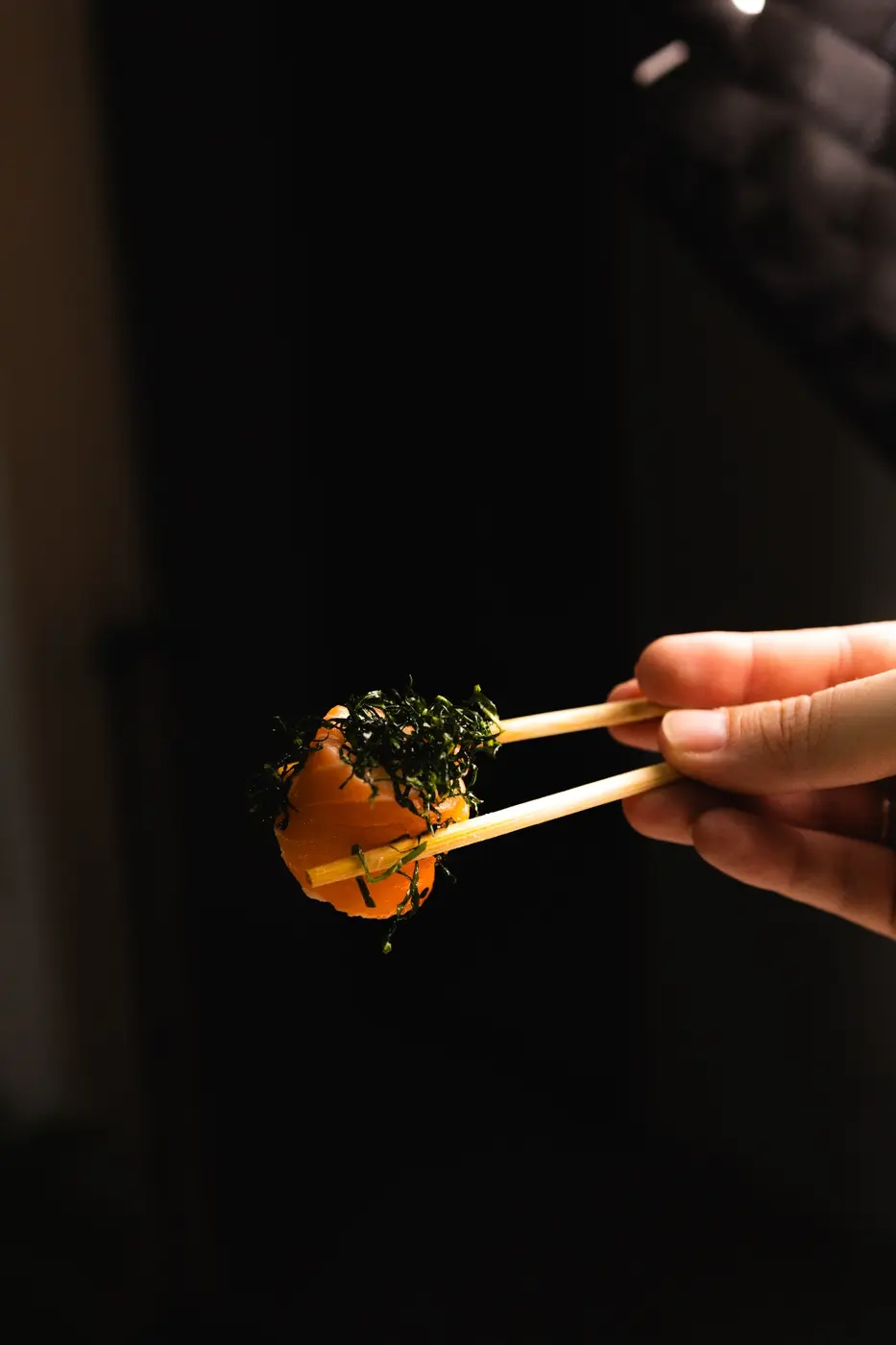 Sushi de salmão segurado com hashis
